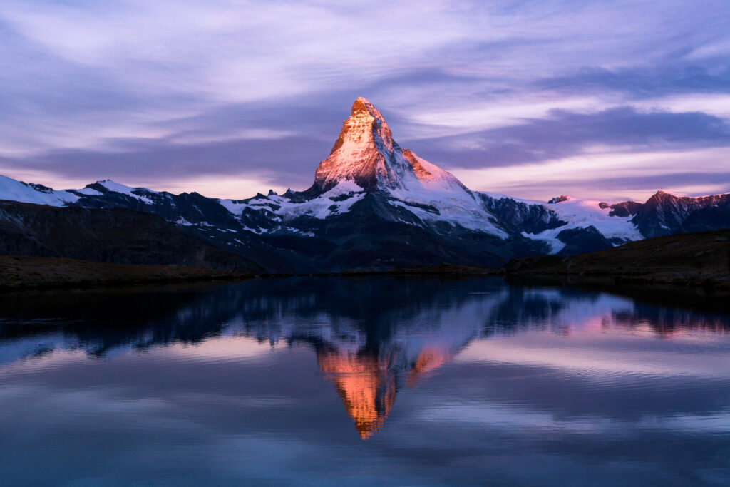 Das Matterhorn spiegelt sich im lila Morgenlicht im Stellisee, oberhalb von Zermatt.