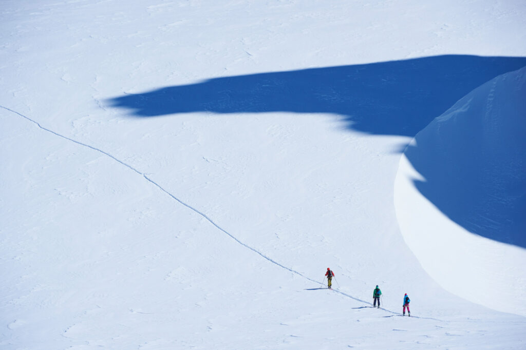 Distant view of three skiers on track, Mont Blanc massif, Graian Alps, France