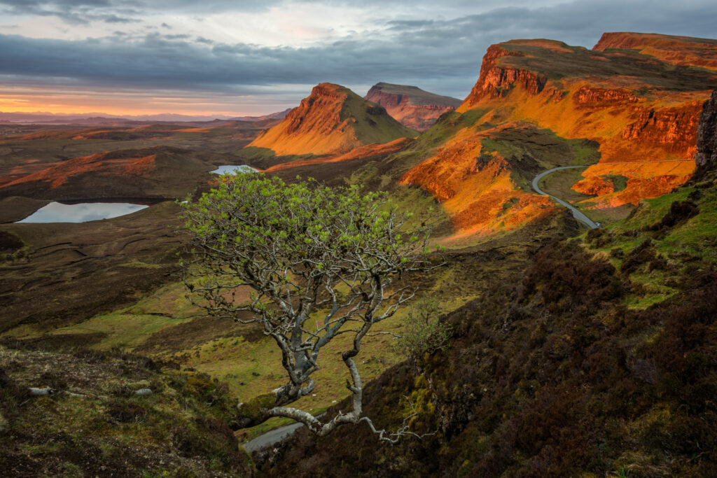 First rays of sun shine a light on the Quiraing mountains at sunrise in the wilderness landscape of Trotternish Ridge on Skye island in Scotland in the UK.