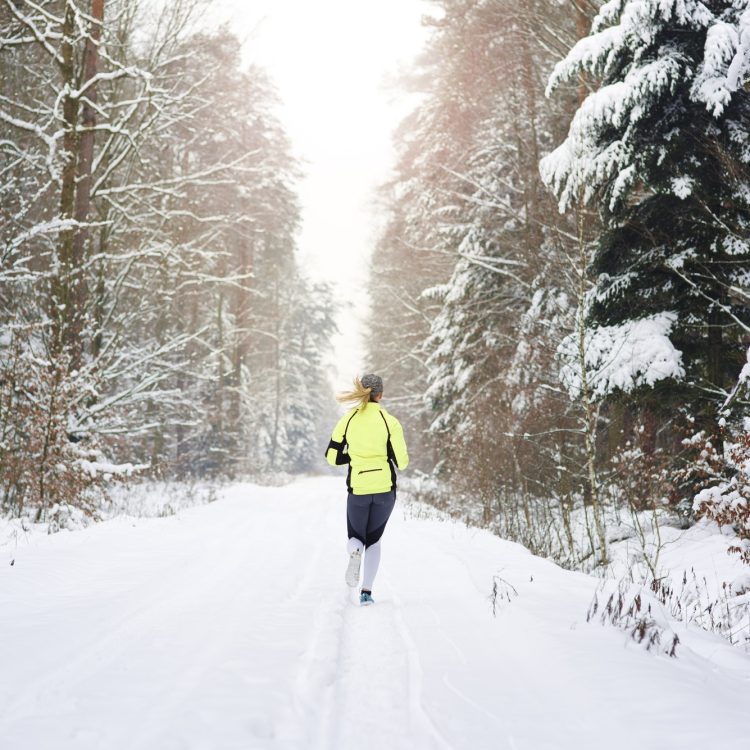Rear view of woman running in winter forest